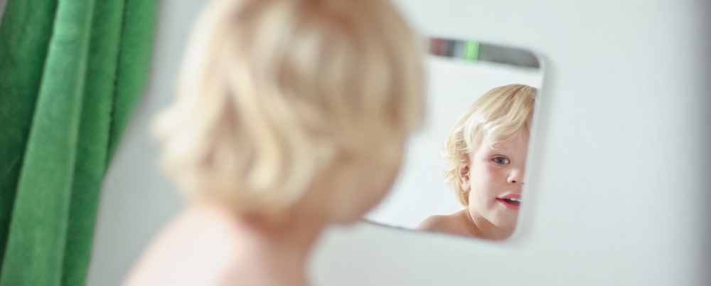 ein Junge schaut in den Spiegel