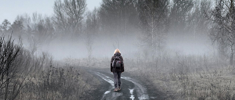 Eine Frau während einer Wanderung durch einen Nebelwald