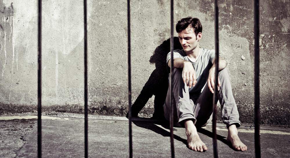 Mann sitzt hinter Gittern