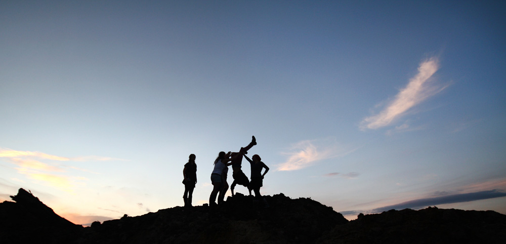 Jugendliche auf einem Hügel gegen das Abendlicht