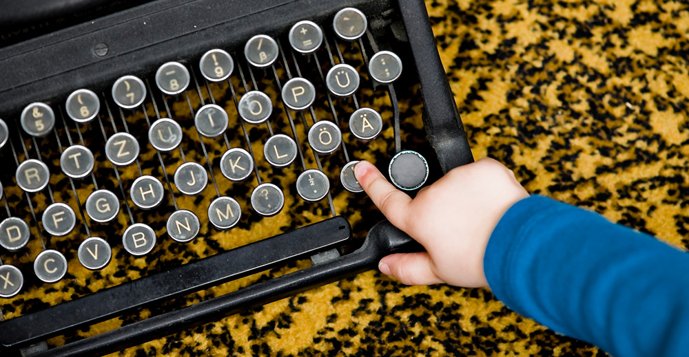 Finger eines Kindes auf einer Schreibmaschine