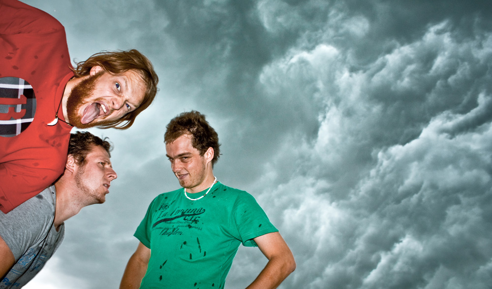 drei junge Männer vor dramatischem Himmel