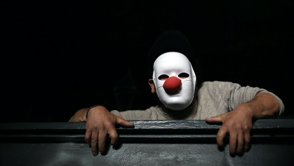 Clown mit Maske im Halbdunkel