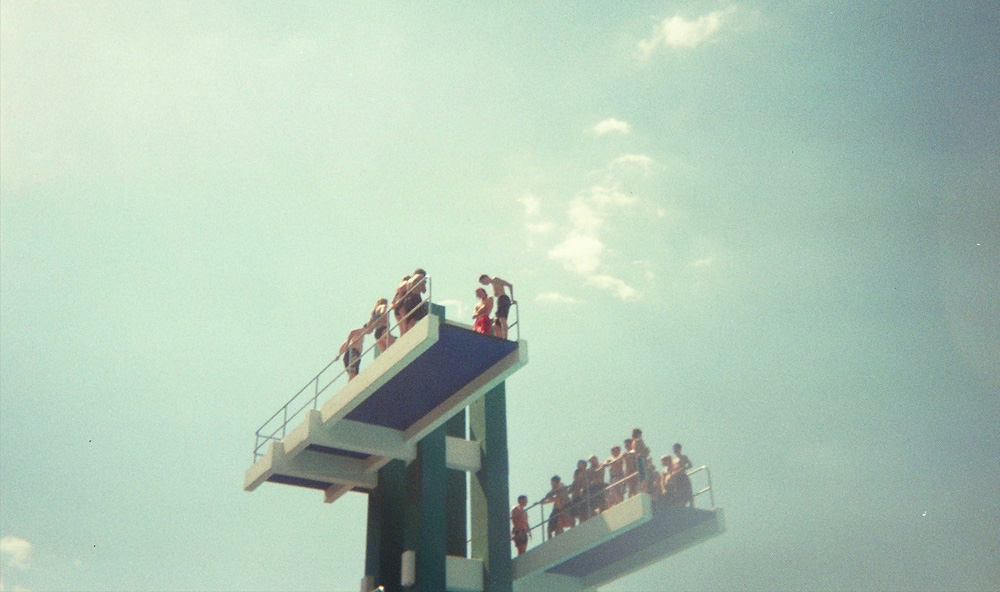 Menschen auf einem Sprungturm im Freibad